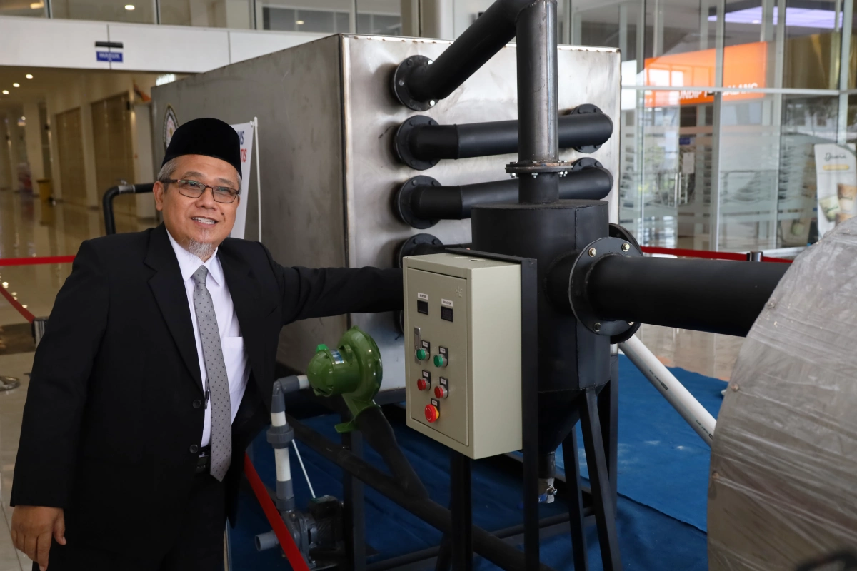 Prof. Ir. Didi Dwi Anggoro, M.Eng., Ph.D., berpose di samping Mesin Pirolisis Dipofuel Gen 3 dalam pameran riset UNDIP.